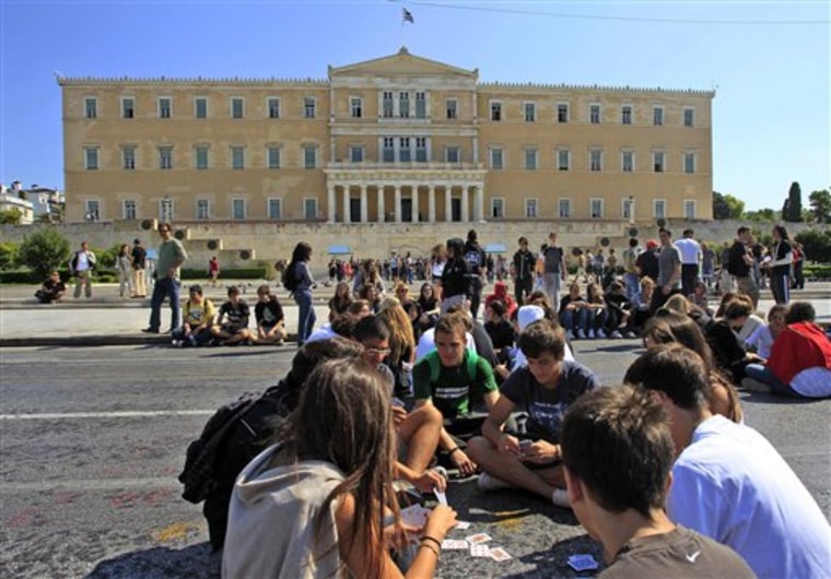 High school students play cards as they block a main avenue during a protest outside the Greek parliament in Athens.